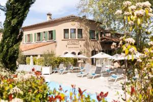 ein Hotel mit Stühlen und Sonnenschirmen vor einem Gebäude in der Unterkunft Hôtel et Restaurant La Bastide Bourrelly - Mathias Dandine - Teritoria in Cabriès