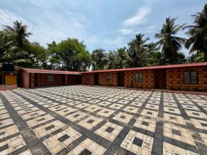 a brick building with a large courtyard with palm trees at AR Cottage in Udupi