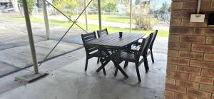a wooden table and chairs sitting next to a brick wall at Little Sanctuary by Book Jervis Bay - Your Perfect Getaway, A Short Stroll to Palm Beach in Sanctuary Point +7 photos