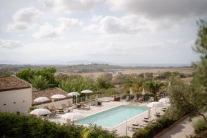 a view of the pool at a resort with chairs and umbrellas at Firriato Hospitality - Baglio Sorìa in Trapani