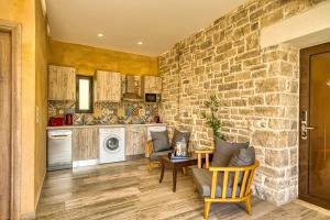 a kitchen with a stone wall and a table and chairs at Olive Luxury Suites - ADULTS ONLY in Kamilari