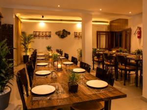 a long wooden table in a restaurant with chairs and tables at Hotel Valna Estate Himalyan View Kausani By HRG in Kausani