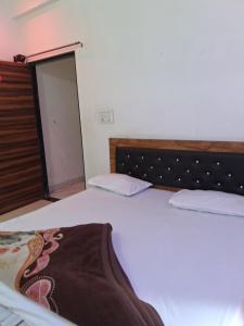 a bedroom with a white bed with a wooden headboard at Khaatuwaale Guest House in Khātu +7 photos