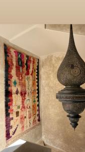a piece of art on a wall next to a rug at Maison Zamane in Marrakesh