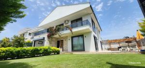 a white house with a lawn in front of it at Villa Kalinda Your Private Sheltered Luxury Villa with Pool Minutes Away from Dalaman Airport in Dalaman