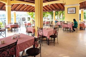 a restaurant with red and white tables and chairs at Riverside Regency Resort in Baga