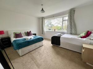 a bedroom with two beds and a window at Large Stylish 5 bed Cambridge House in Harston