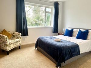 a bedroom with a bed and a chair and a window at Large Stylish 5 bed Cambridge House in Harston +5 photos