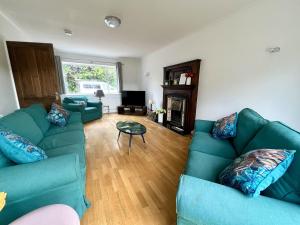 a living room with two green couches and a fireplace at Large Stylish 5 bed Cambridge House in Harston