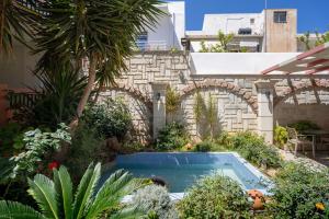 a garden with a swimming pool in front of a building at Flisvos in Sitia