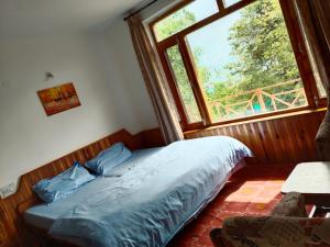 a bed in a room with a large window at Monal House in Manāli