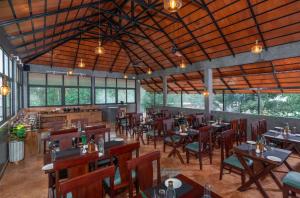 a restaurant with wooden tables and chairs and windows at Citadel Boutique Hotel in Thekkady