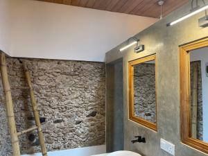 a bathroom with a stone wall and a mirror at Villa Flamingo in Ahangama