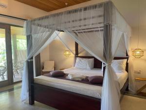 a bedroom with a canopy bed with white curtains at Villa Flamingo in Ahangama