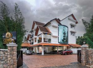 a large white house with a brick driveway at Citadel Boutique Hotel in Thekkady