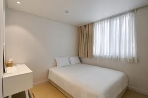 a bedroom with a white bed and a window at soul stay in Busan