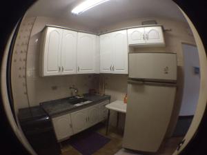 a kitchen with white cabinets and a sink and a refrigerator at Edificio Namberuã in Guarujá