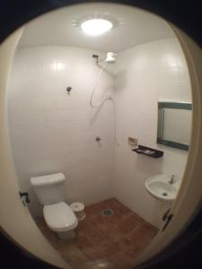 a white bathroom with a toilet and a sink at Edificio Namberuã in Guarujá