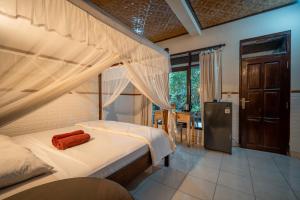 a bedroom with a canopy bed with a red towel on it at Bismajaya Bungalow in Ubud
