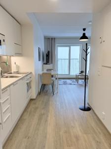 a kitchen with white cabinets and a dining room with a table at Foliate Living Varpu in Jyväskylä +4 photos