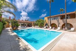 a swimming pool in front of a house with palm trees at Villa Thalissa by Perle di Puglia in Taranto