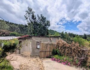 an old house on a dirt road next to a fence at ImuHira Campsite in Nyamasheke