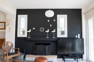 a living room with a black wall with a fireplace and a tv at Marilia GuestHouse - Seaside Retreat in Evia in Agia Anna +21 photos