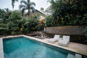 a swimming pool with two white chairs next to it at Bismajaya Bungalow in Ubud +63 photos