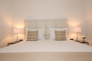 1 cama blanca con almohadas blancas y 2 lámparas en B&B Demar Residence & Dependance en Zadar