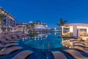 a swimming pool with chairs and buildings at night at Royal Atlantis Icon in Side