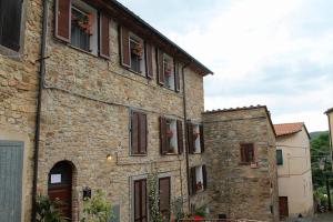 an old stone building with flowers in the windows at Casa Vacanze in Borgo in Monteverdi Marittimo