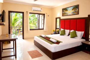 a bedroom with a large bed with a red headboard at Riverside Regency Resort in Baga