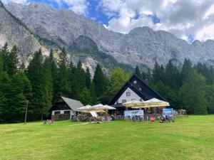 a building with tables and umbrellas in a field at Rooms Malina I Peaceful Stay Near Bled & Mountain Views in Blejska Dobrava
