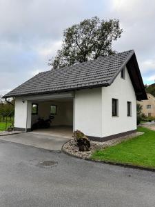 a white house with a garage and a tree at Bloom Residence Gomzi in Naklo