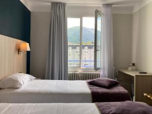 a hotel room with two beds and a window at Hôtel Christina Lourdes in Lourdes