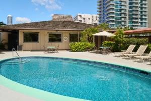 a swimming pool with chairs and a building at Pagoda Hotel in Honolulu