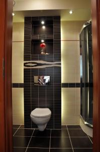 a bathroom with a toilet and a black tile wall at Color Apartment in Kraków