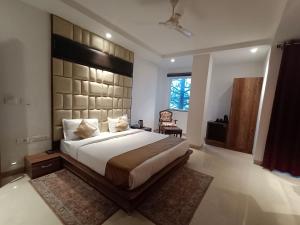 a bedroom with a large bed with a large headboard at RR Hotel & Resort by Sonachi in Dharamshala