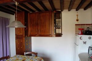 una cucina con armadi in legno, tavolo e frigorifero di Casa Vacanze in Borgo a Monteverdi Marittimo