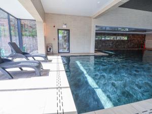 a swimming pool in a house with chairs in it at Willerby Malton in Ruthin