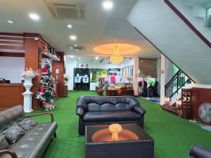 a living room with leather furniture and a christmas tree at NJ INTHAI Hotel in Sathani Chiang Rak