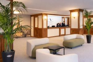 a lobby with two chairs and a counter with people at LVG Hotel Collection - La Bussola in Novara