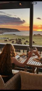 a woman sitting at a table with glasses of wine at Waves & Wildlife Cottages Kangaroo Island in Stokes Bay