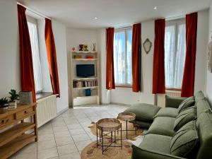 a living room with a green couch and red curtains at Le Néococoon in Neufchâteau