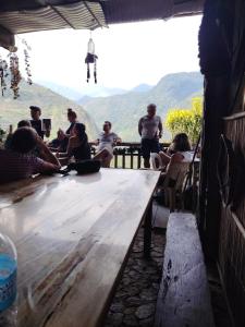 a group of people sitting around a wooden table at Ramon's Homestay in Banga-an