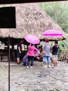 a group of people standing under umbrellas in front of a hut at Ramon's Homestay in Banga-an