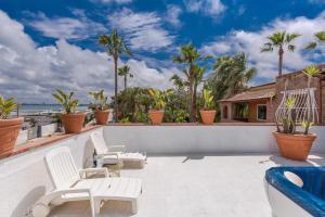 a patio with white chairs and palm trees at Villa Thalissa by Perle di Puglia in Taranto