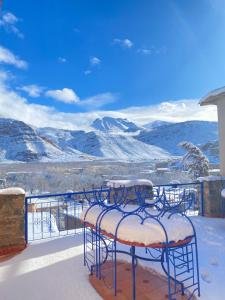 a balcony with snowcovered chairs and a view of mountains at Kasbah Ait Bouguemez in Agouti