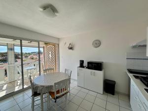 a kitchen with a table and a dining room with a balcony at Le Surf in Mimizan-Plage
