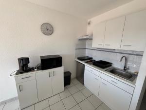 a kitchen with a sink and a clock on the wall at Le Surf in Mimizan-Plage